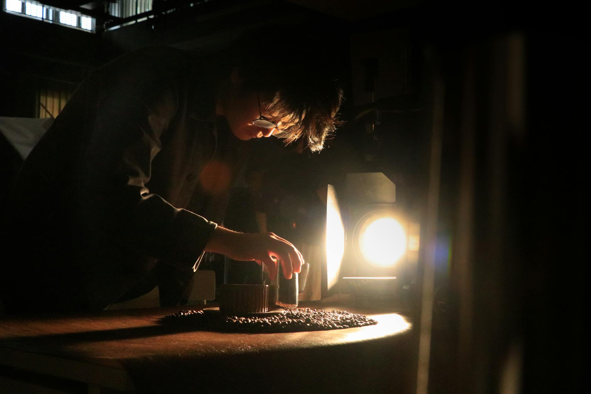 Rzemieślnik skupiony na precyzyjnej pracy przy warsztacie w mocnym świetle