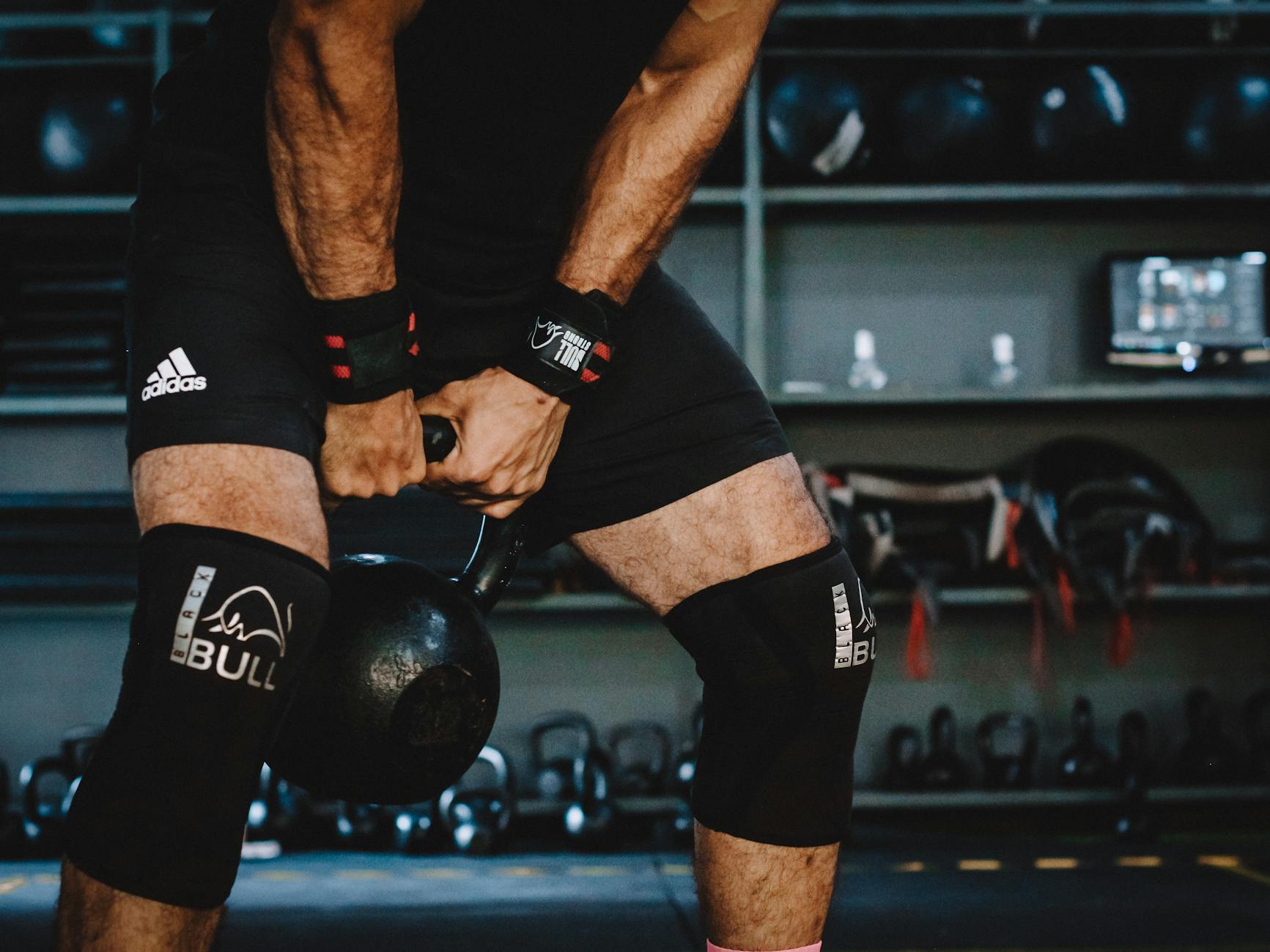 Mężczyzna unosi kettlebell na siłowni podczas intensywnego treningu