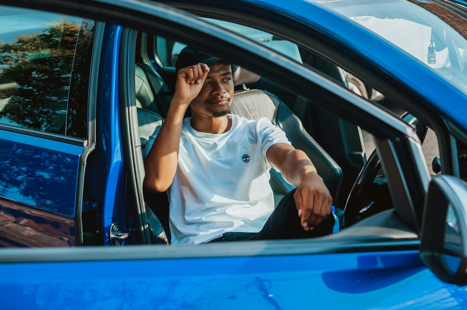 Młody mężczyzna w białej koszuli siedzi wygodnie w niebieskim aucie