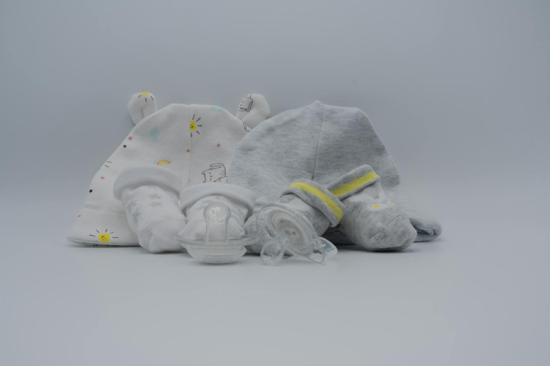 Pastelowe czapeczki, skarpetki i smoczek przygotowane dla noworodka