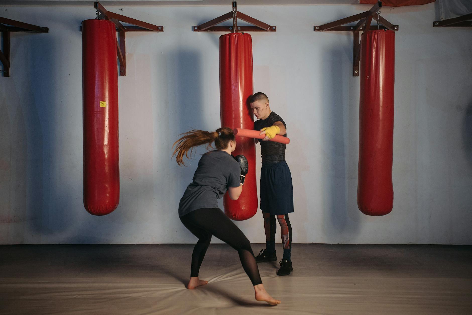 Kobieta trenująca boks z trenerem na sali sportowej