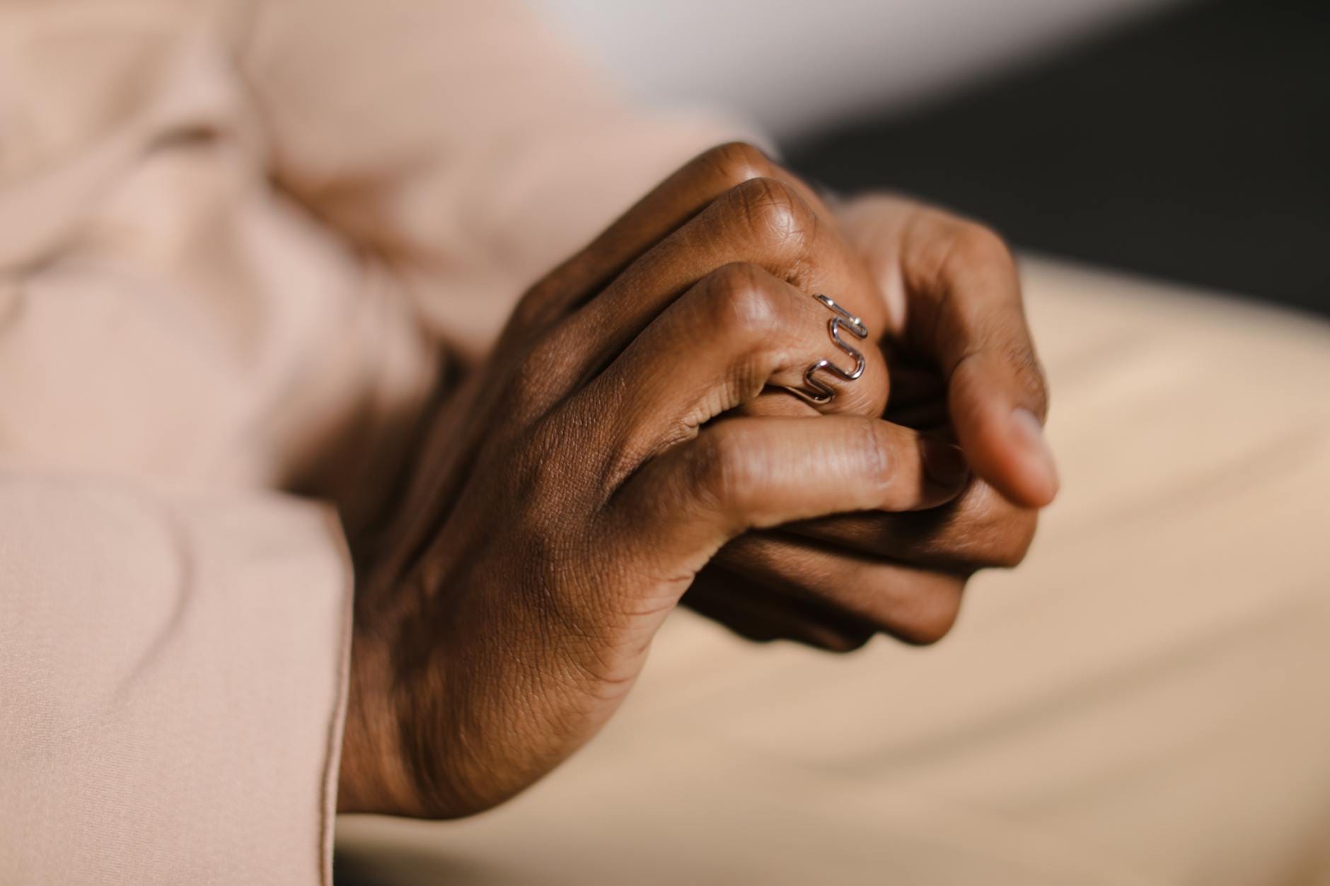 Zbliżenie splecionych dłoni z ozdobnym pierścionkiem w kształcie węża