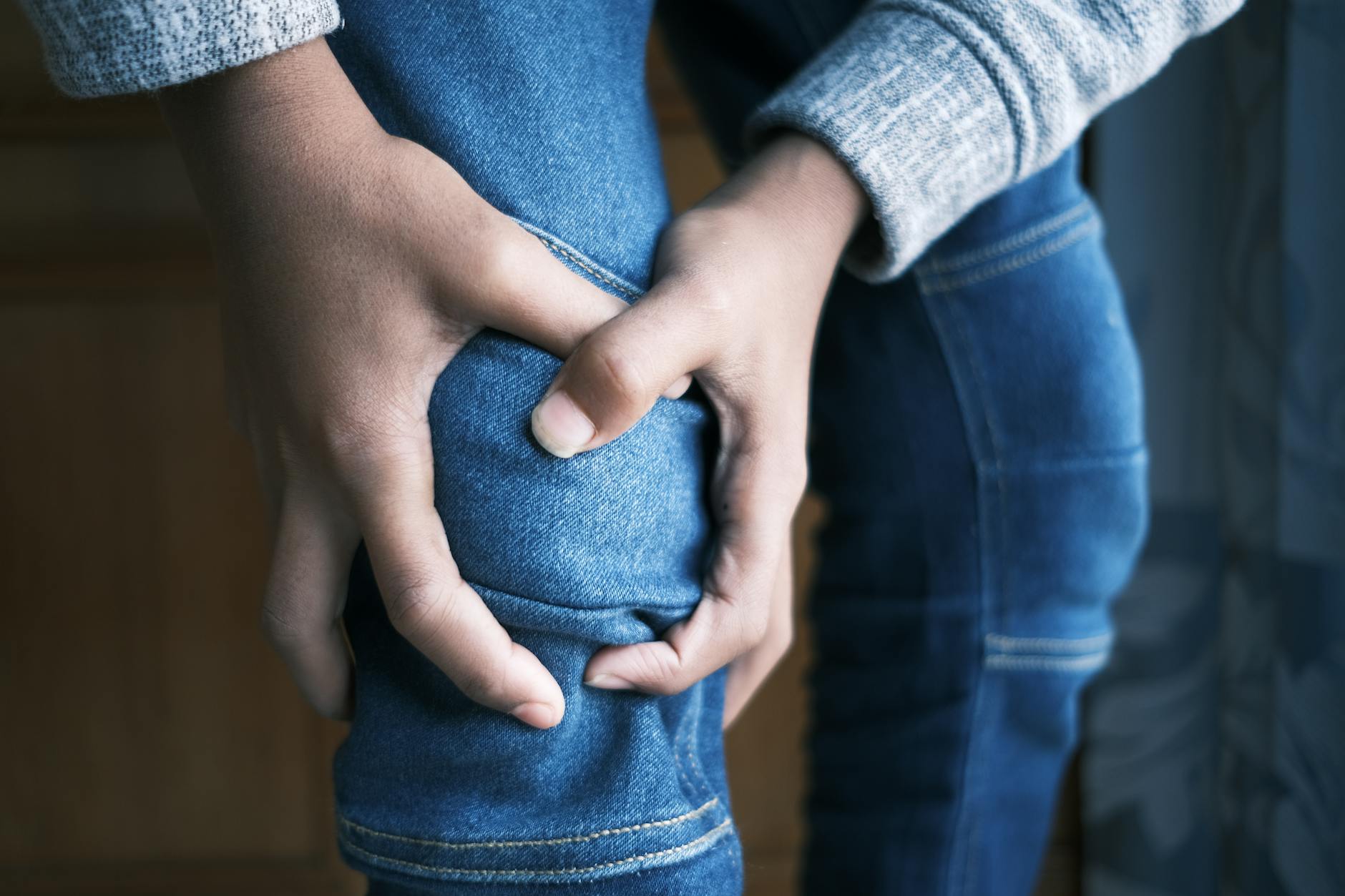 Zbliżenie na dłoń kierowcy trzymającą bolące kolano w dżinsach