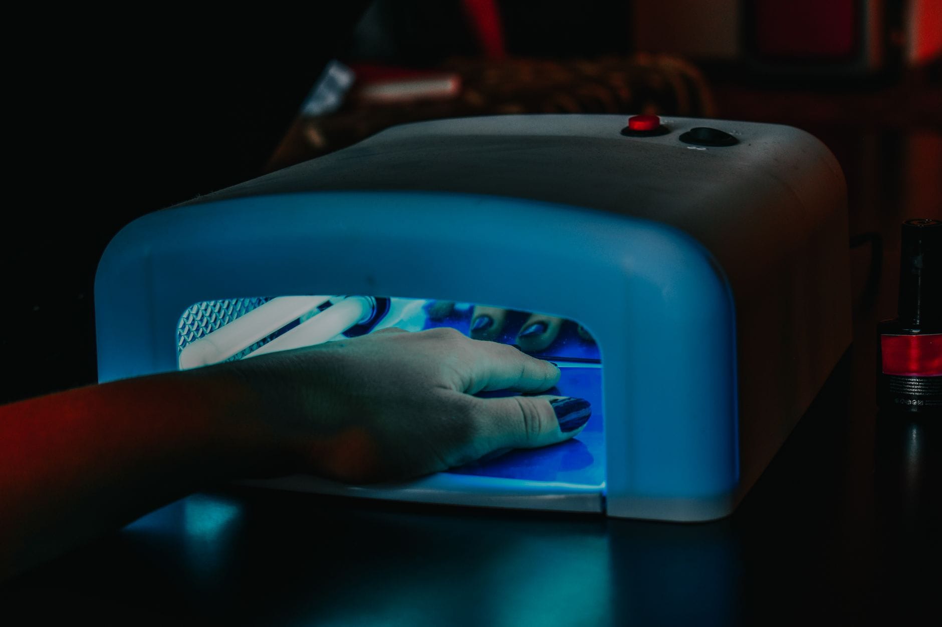 Dłoń z hybrydowym manicure utwardzana pod niebieską lampą LED Dłoń z hybrydowym manicure utwardzana pod niebieską lampą LED