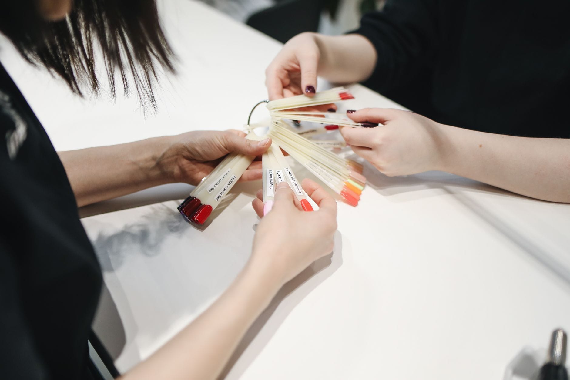 Dłonie wybierające kolor lakieru hybrydowego w salonie manicure