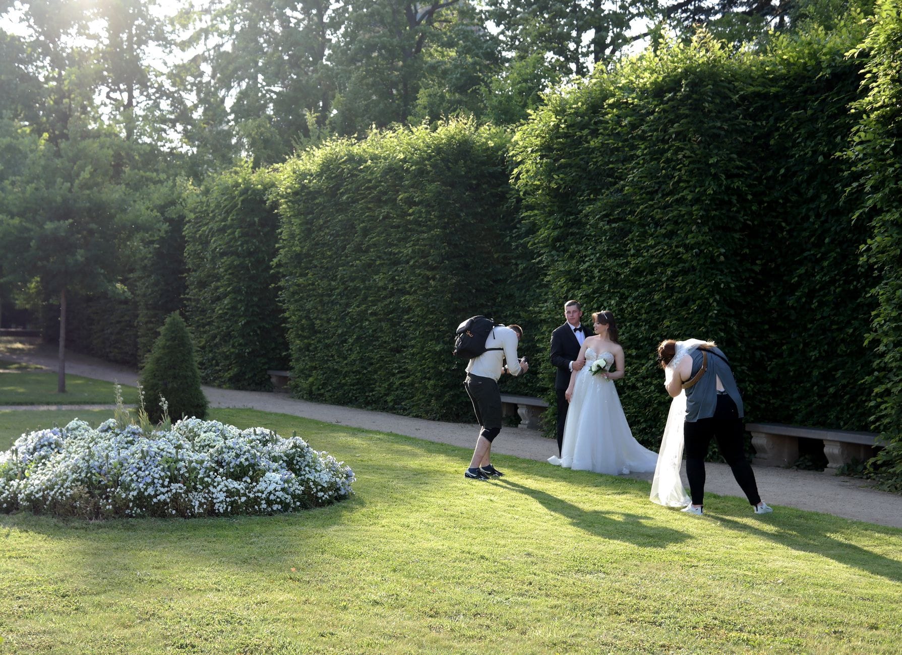 Para młoda pozuje fotografom w słonecznym ogrodzie