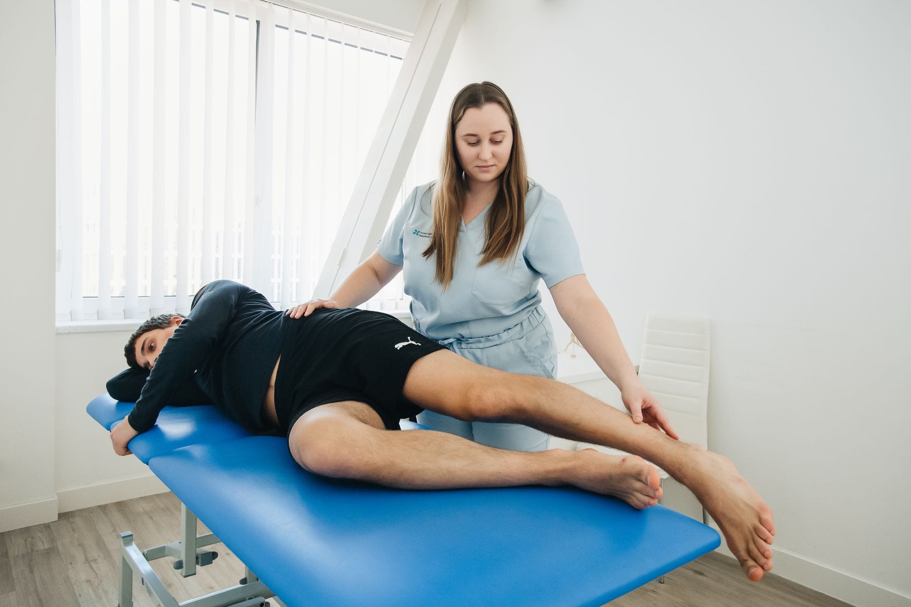 Fizjoterapeuta koryguje ustawienie miednicy pacjentki podczas rehabilitacji