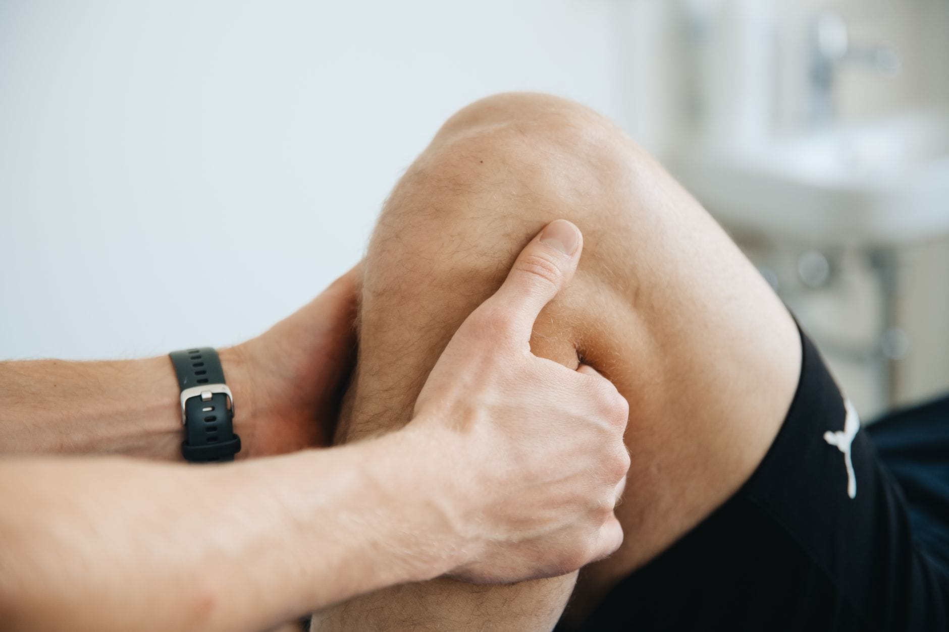 Rekonstrukcja ACL: jak wygląda powrót do biegania etapami? Fizjoterapeuta masuje kolano pacjenta po rekonstrukcji ACL