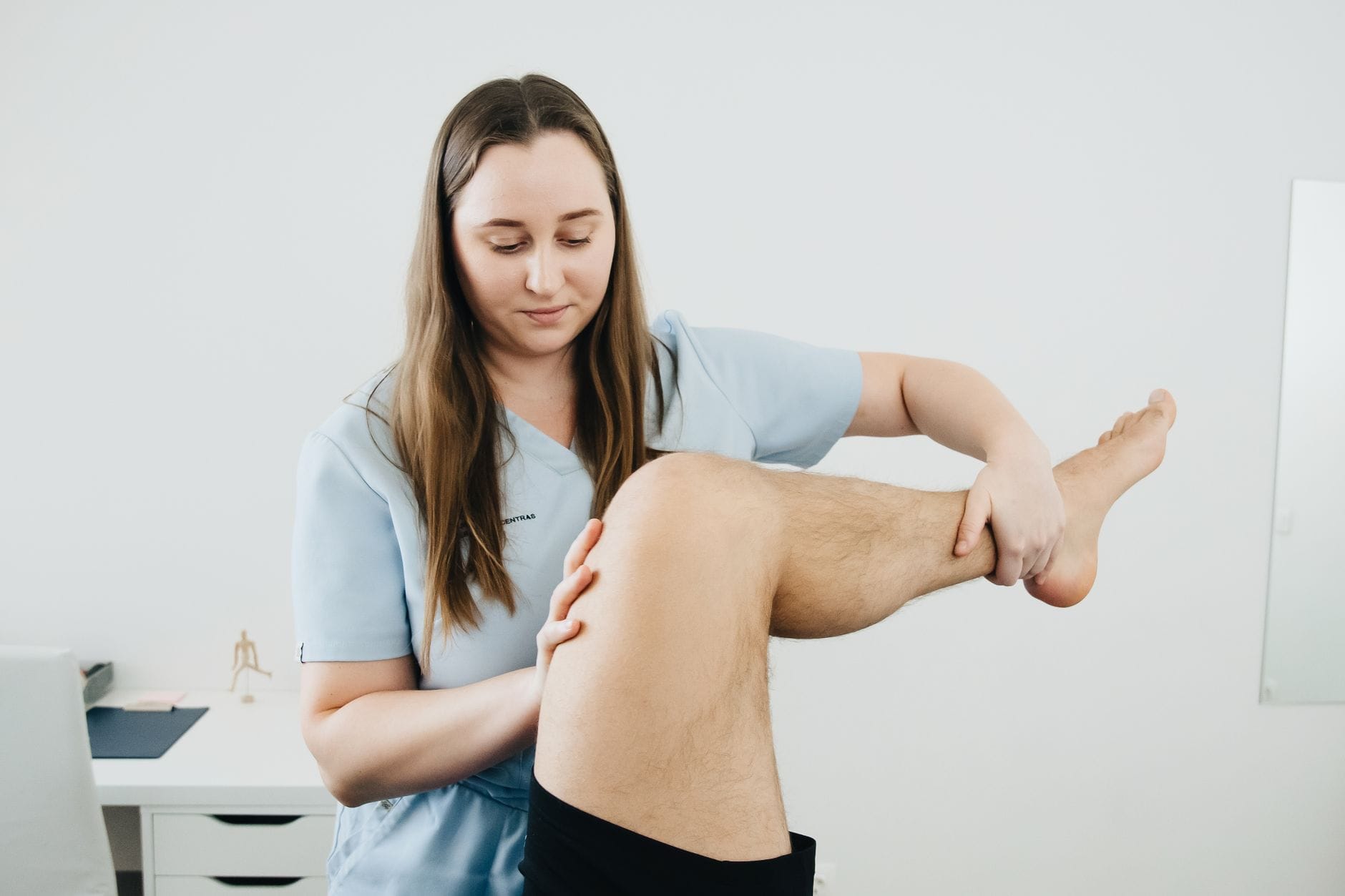 Fizjoterapeuta prowadzi rehabilitację nogi pacjenta po rekonstrukcji ACL