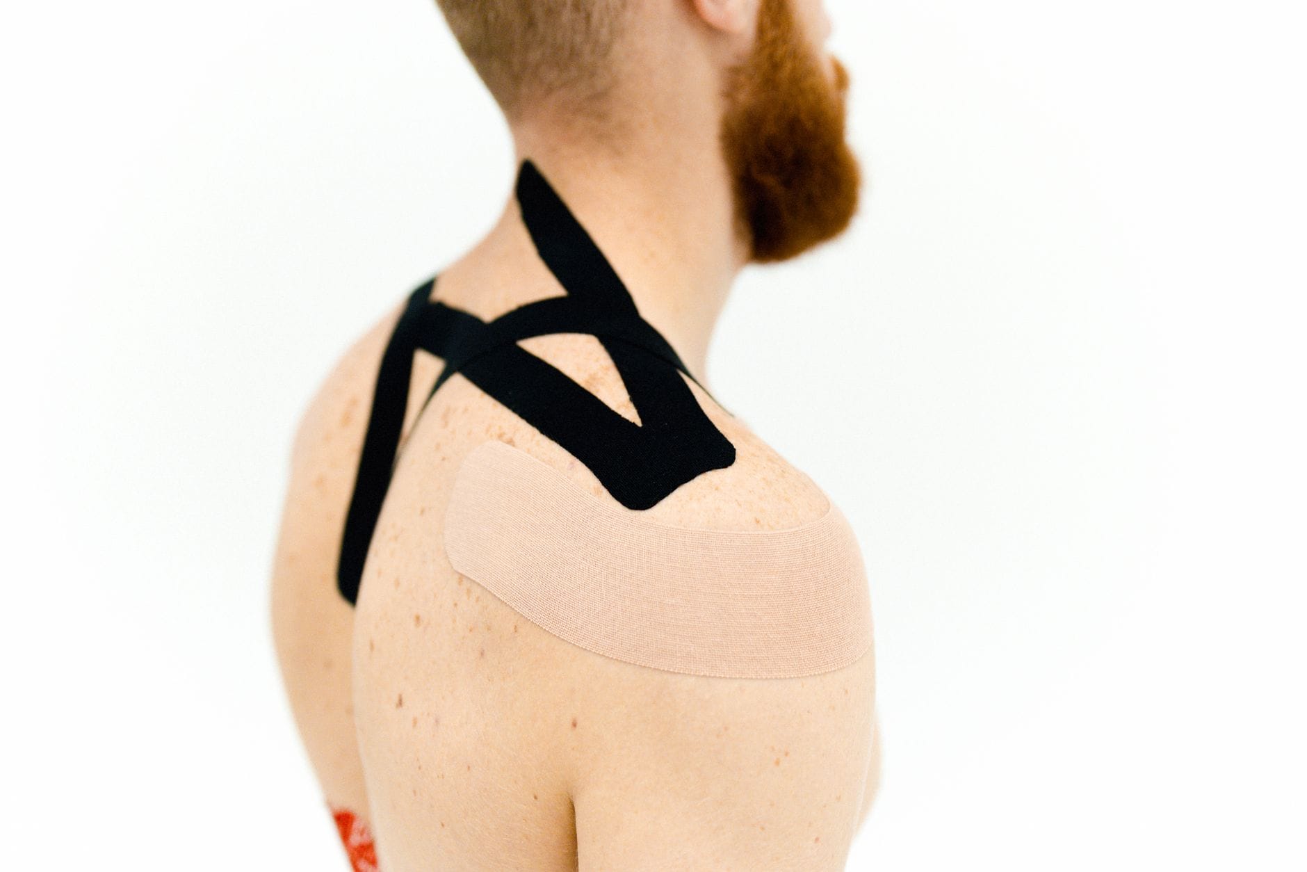 Zbliżenie na kinesiotaping na barku mężczyzny przy terapii stożka rotatorów